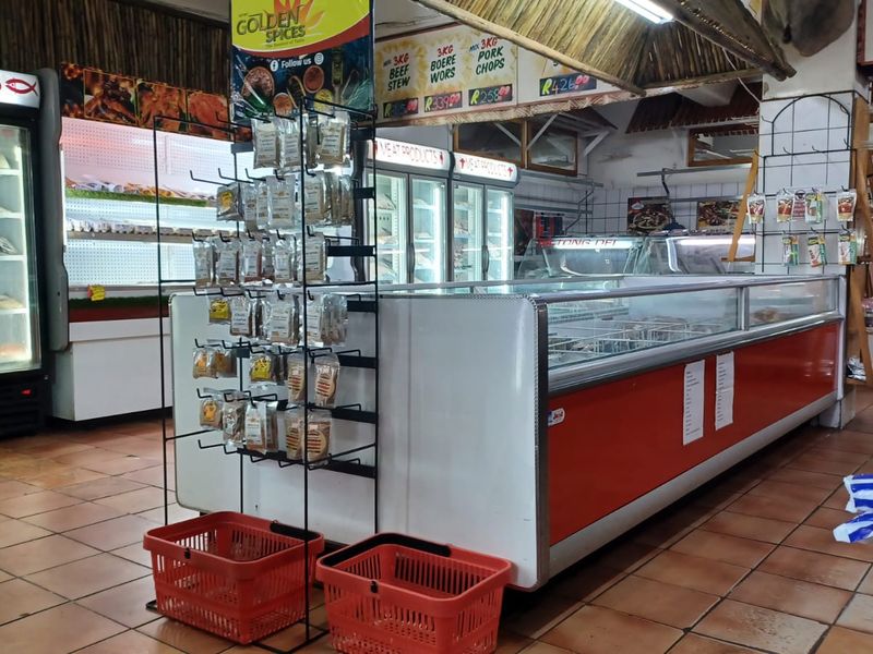 A commercial retail space featuring built-in refrigeration units, display counters, and tiled flooring, currently set up as a butchery or food retail outlet.