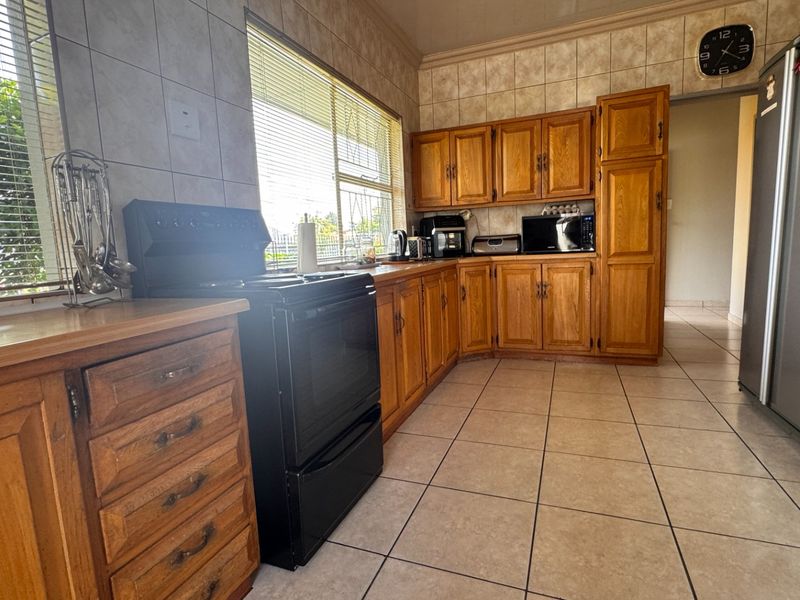 A functional kitchen featuring traditional wooden cabinetry, tiled backsplash, and tiled flooring, providing ample storage and workspace for daily meal preparation.