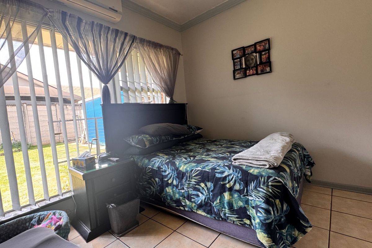 A bedroom featuring tiled flooring, a wall-mounted air conditioning unit, and a sliding glass door providing access to the exterior.