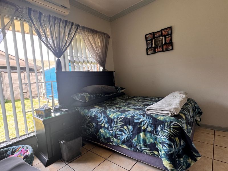 A bedroom featuring tiled flooring, a wall-mounted air conditioning unit, and a sliding glass door providing access to the exterior.