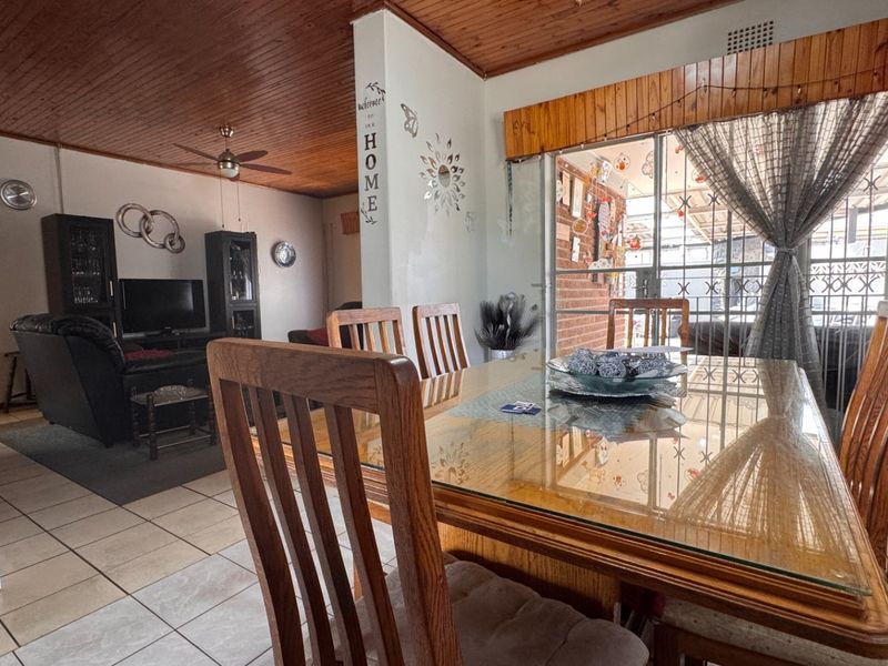 Open plan living and dining area featuring a wooden tongue and groove ceiling, ceramic tiled flooring, and a sliding door with security gate access.