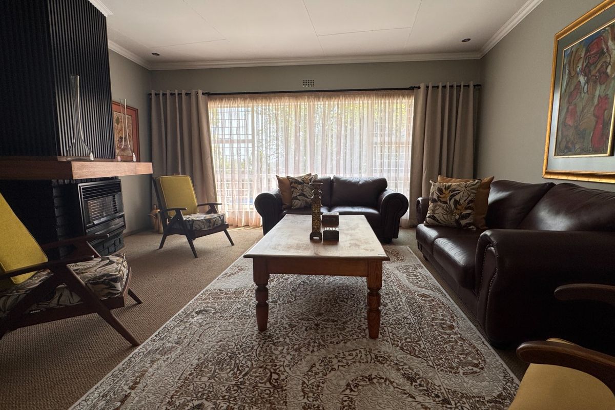 A comfortable living room featuring a built-in fireplace with a dark feature wall, recessed lighting, and large sliding doors providing natural light.