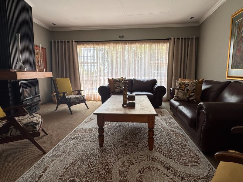A comfortable living room featuring a built-in fireplace with a dark feature wall, recessed lighting, and large sliding doors providing natural light.