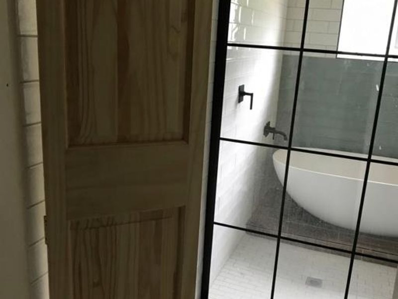 Modern bathroom featuring a freestanding bathtub, black framed glass shower enclosure, subway wall tiling, and wood-look floor tiles.
