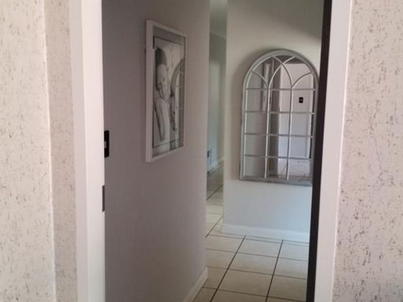 A view through a doorway into a tiled hallway with neutral wall finishes and clean architectural lines.