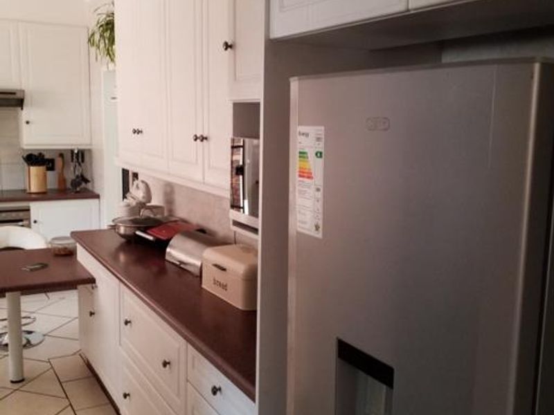 A functional kitchen featuring white cabinetry, dark laminate countertops, and tiled flooring, providing a practical workspace with integrated appliances.