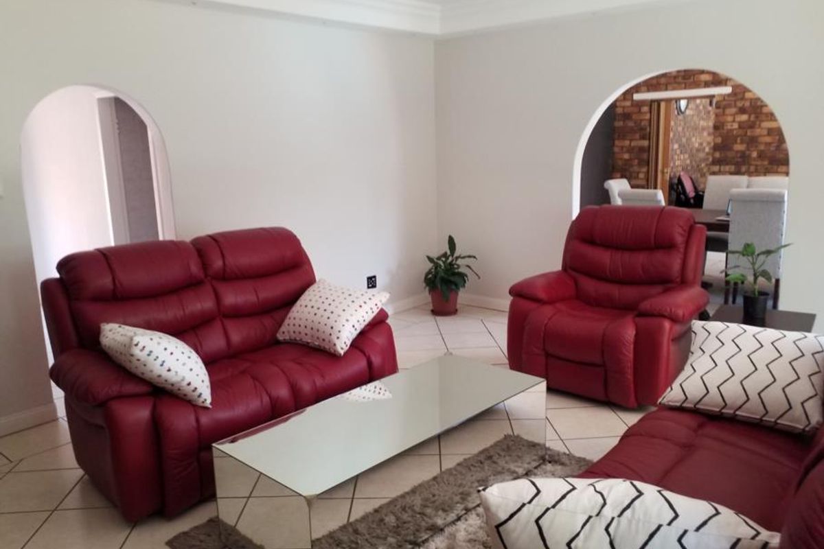 A living room featuring tiled flooring, coved ceilings, and arched doorways leading to adjacent spaces.