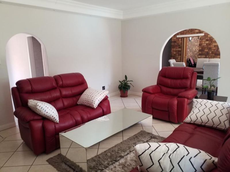 A living room featuring tiled flooring, coved ceilings, and arched doorways leading to adjacent spaces.