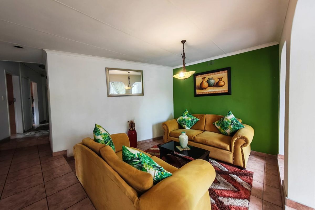 A comfortable living room featuring tiled flooring, a coved ceiling, and a central pendant light fixture, providing a functional and inviting space.