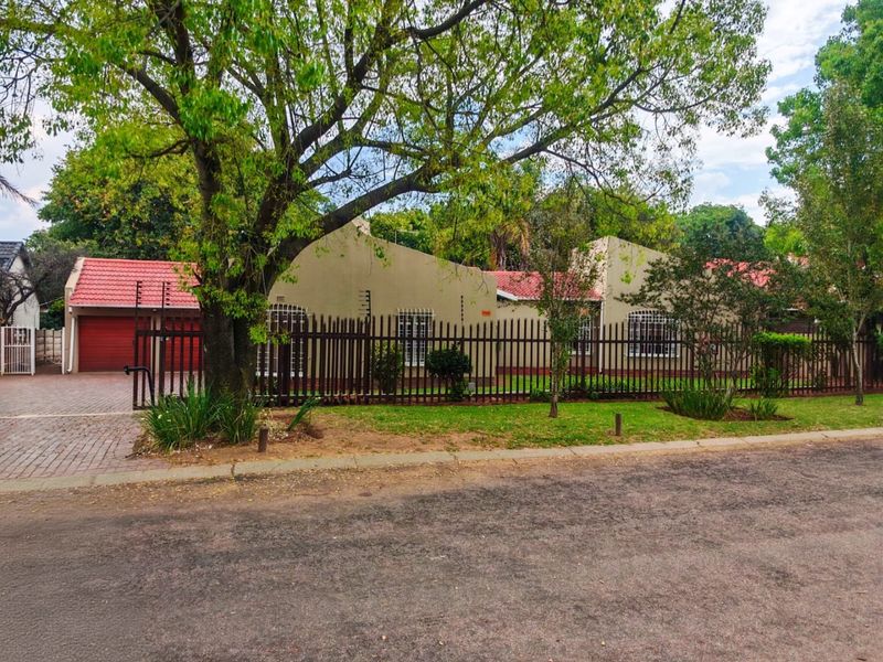 Front view of a single-story residential property featuring a tiled roof, paved driveway, and secure perimeter fencing with integrated security measures.