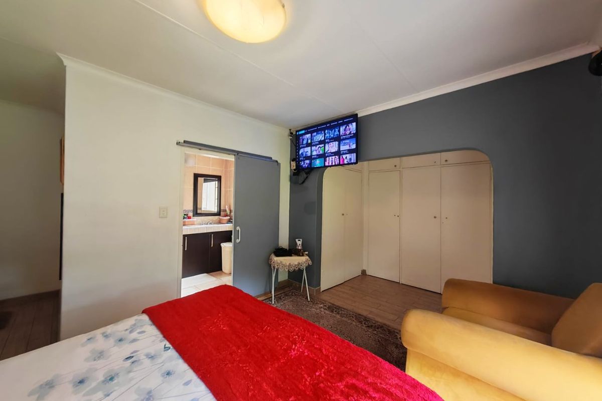 A bedroom featuring built-in cupboards, a sliding door leading to an en-suite bathroom, and a central ceiling light fixture.