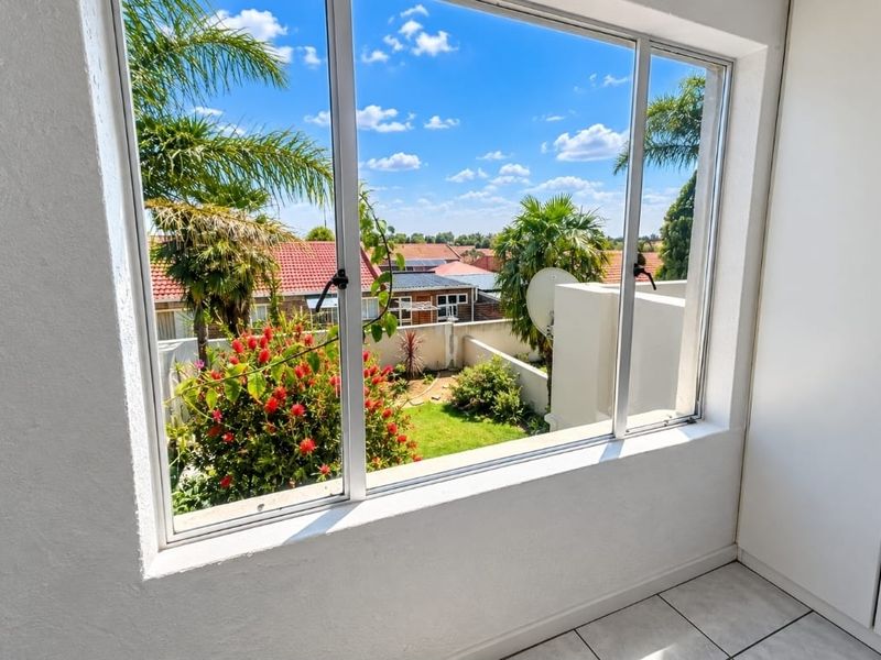 A bright interior space featuring a large window with a clear view overlooking a private garden and surrounding residential neighborhood.