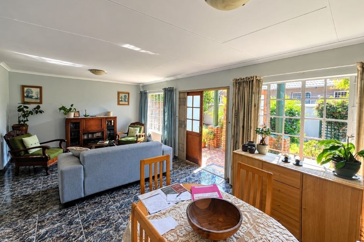 Spacious living area featuring tiled flooring, large windows providing natural light, and direct access to an outdoor patio area.