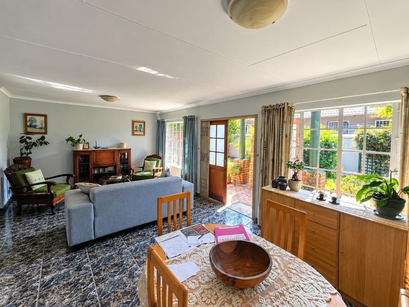 Spacious living area featuring tiled flooring, large windows providing natural light, and direct access to an outdoor patio area.