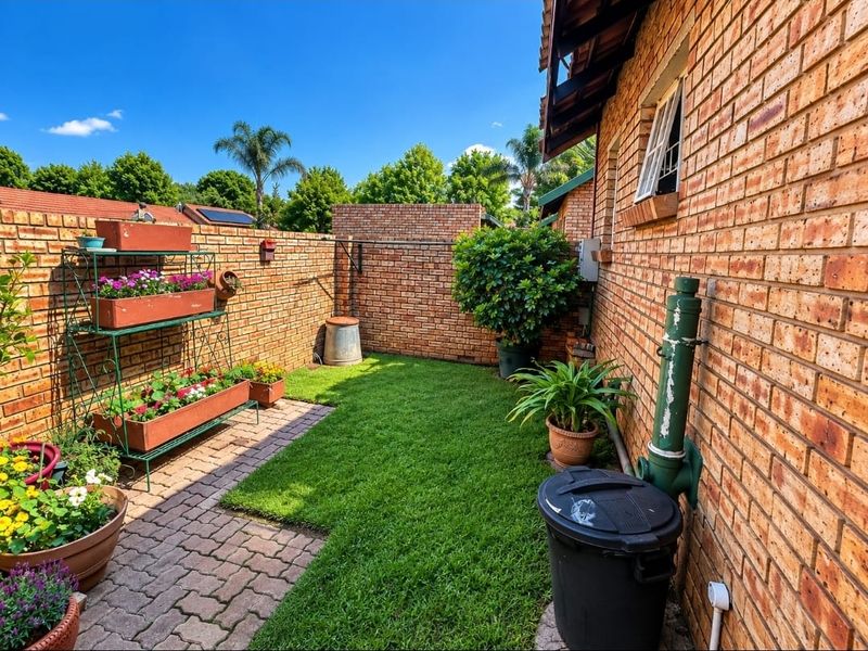 A private rear garden area featuring a brick boundary wall, paved walkway, and a small lawn section.