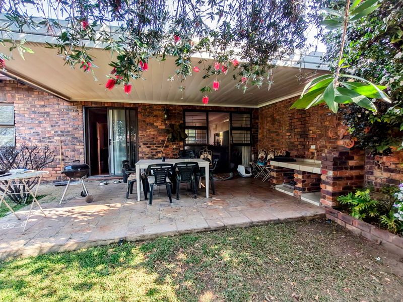 Covered outdoor patio featuring a built-in brick braai, paved flooring, and direct access to the interior through sliding glass doors.