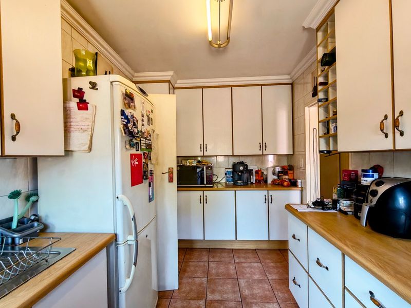 A functional kitchen featuring laminate countertops, ample built-in cabinetry, tiled backsplash, and ceramic floor tiles, offering a practical layout for daily use.