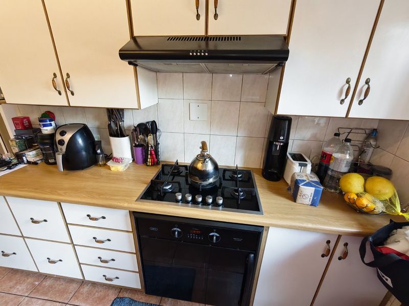 A functional kitchen area featuring built-in cabinetry, a gas hob, an integrated oven, and a tiled splashback with wood-look laminate countertops.