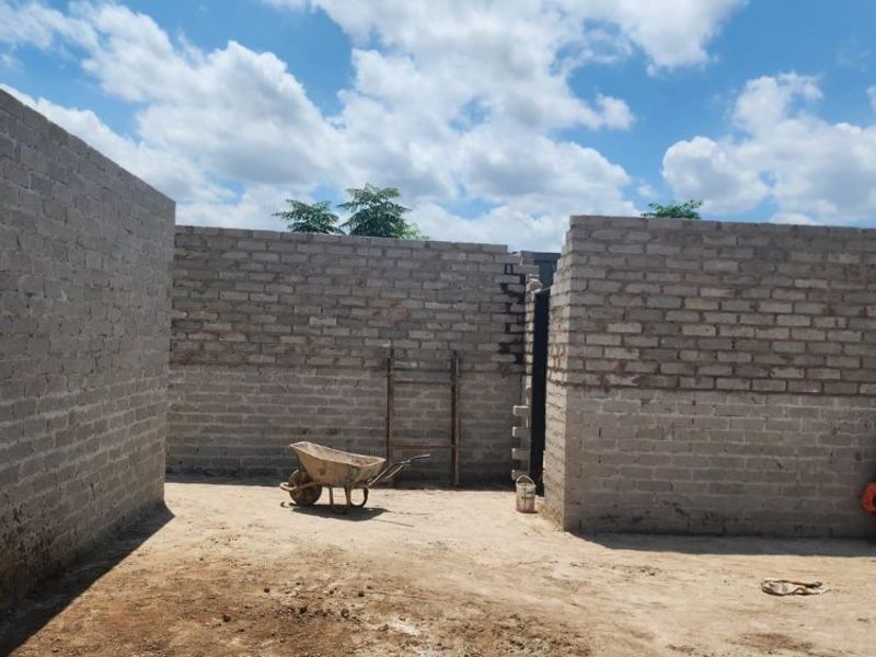 An unfinished outdoor area featuring exposed brick walls under construction, representing a shell-stage property development project.