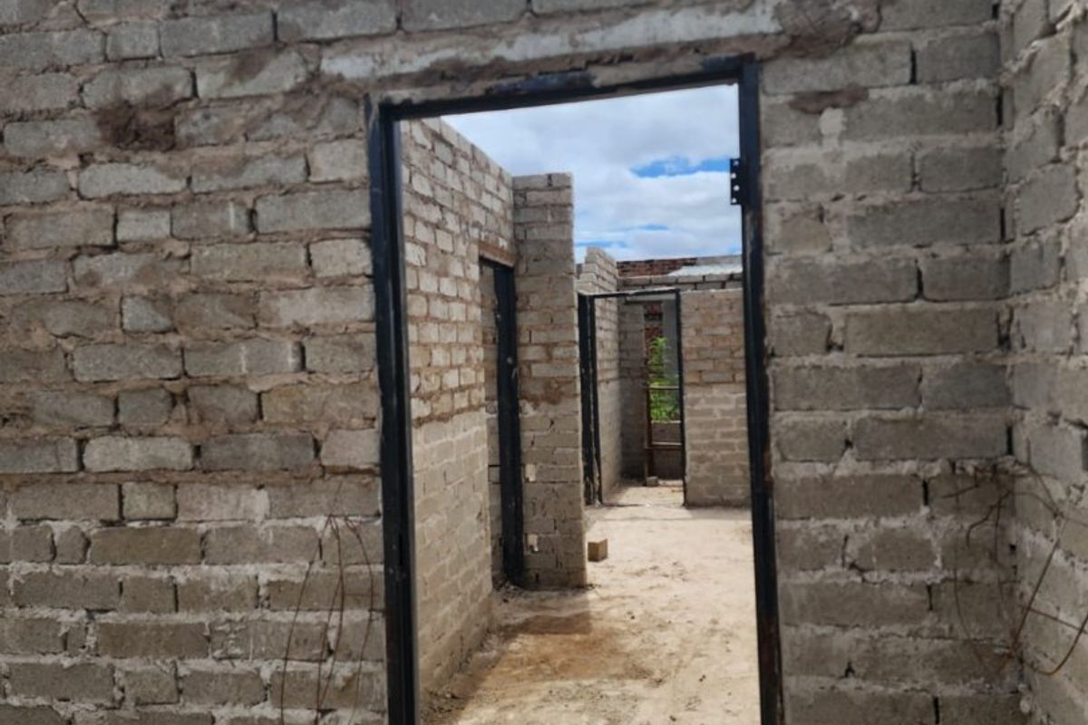 An unfinished construction site showing exposed brick walls and metal door frames, indicating a property in the early stages of development.