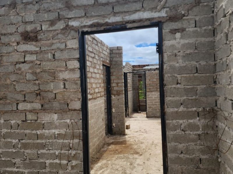 An unfinished construction site showing exposed brick walls and metal door frames, indicating a property in the early stages of development.