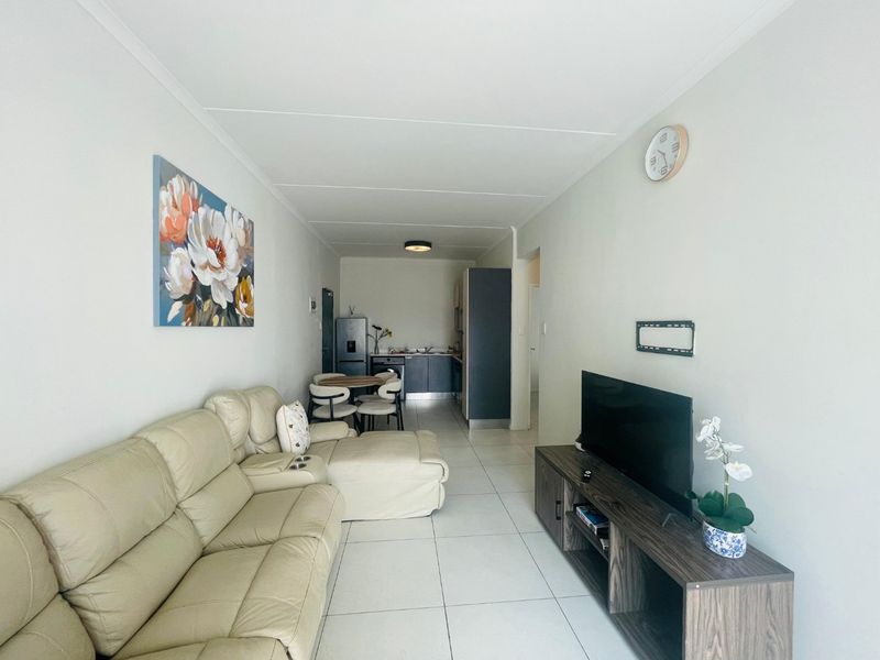 An open-plan living and kitchen area featuring neutral tiled flooring and functional built-in cabinetry, creating a cohesive and practical living space.