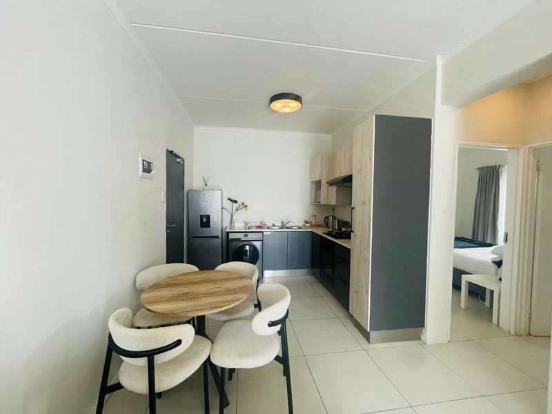 Modern open-plan kitchen featuring sleek built-in cabinetry, integrated appliances, and tiled flooring, seamlessly flowing into the adjacent living and bedroom areas.