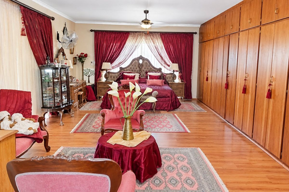 Spacious bedroom featuring extensive wall-to-wall built-in wooden cupboards, laminate flooring, and a ceiling fan.