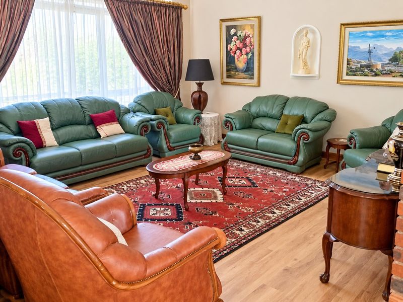 A spacious living room featuring laminate flooring, an exposed brick pillar, and a recessed wall niche, offering a comfortable and traditional living space.