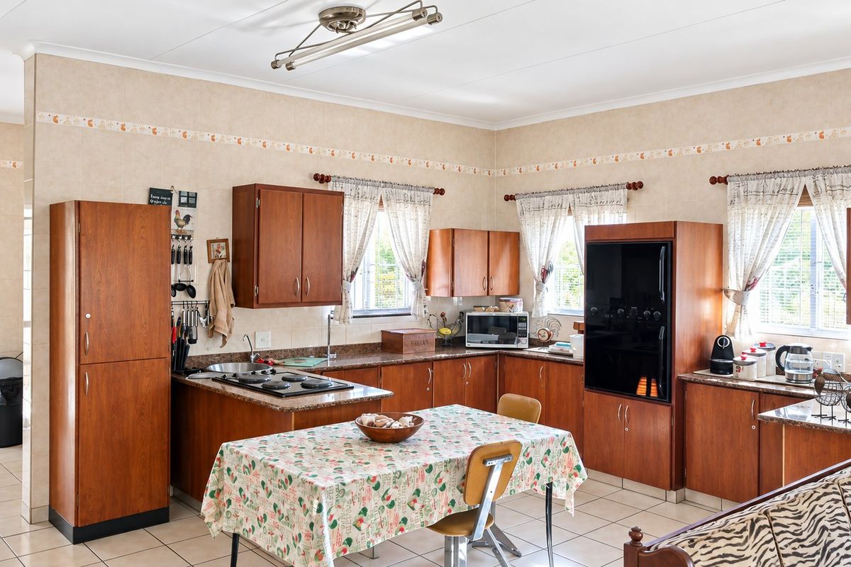 A functional kitchen featuring traditional wooden cabinetry, laminate countertops, built-in oven and hob, and tiled flooring, offering a classic layout with ample storage space.