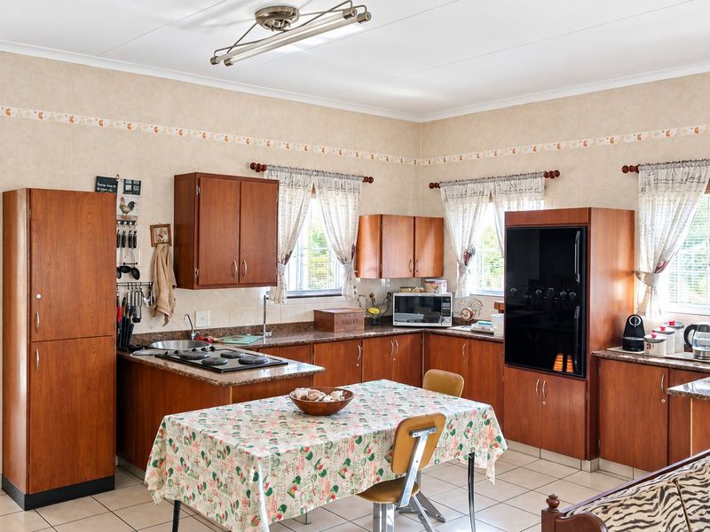 A functional kitchen featuring traditional wooden cabinetry, laminate countertops, built-in oven and hob, and tiled flooring, offering a classic layout with ample storage space.