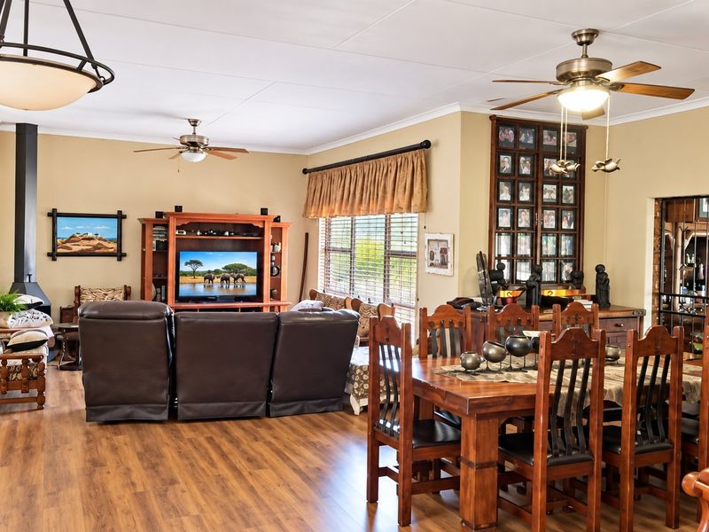 Spacious open-plan living and dining area featuring laminate flooring, ceiling fans, and a cozy freestanding fireplace, offering a versatile layout for family living.