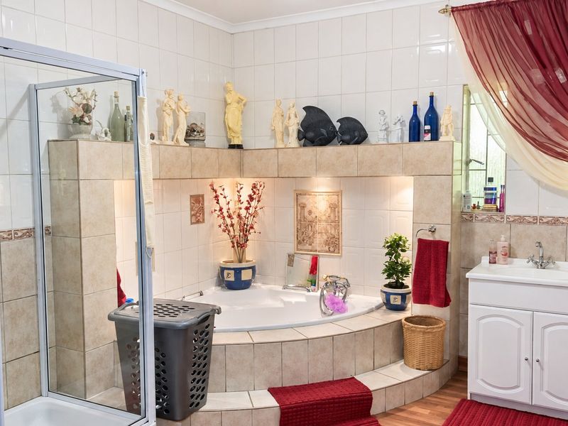 A functional bathroom featuring a corner bathtub, a separate shower enclosure, and a vanity unit with a basin, finished with neutral wall tiling.