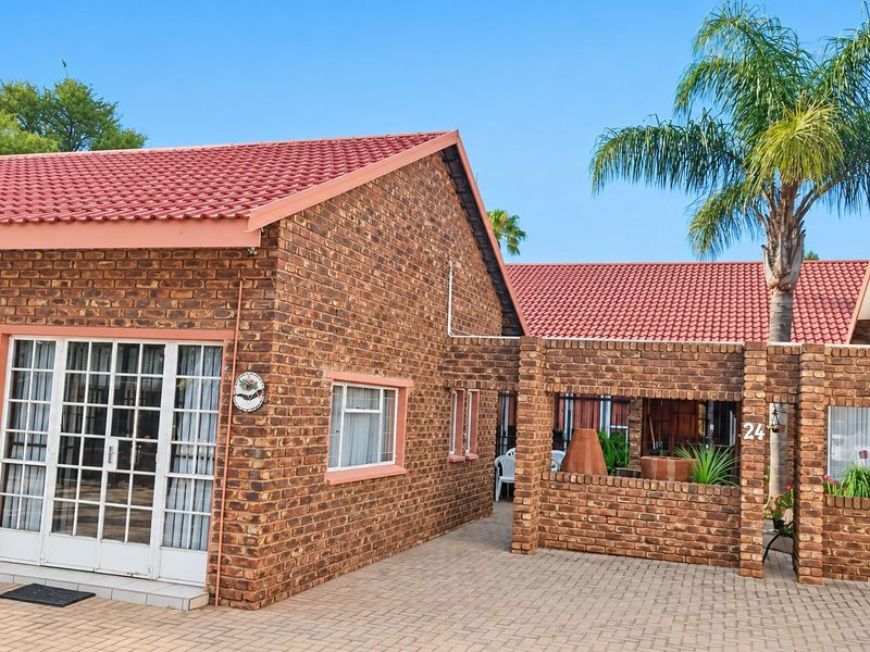 Front exterior view of a face brick house featuring a tiled roof, paved driveway, and a sliding glass door entrance.