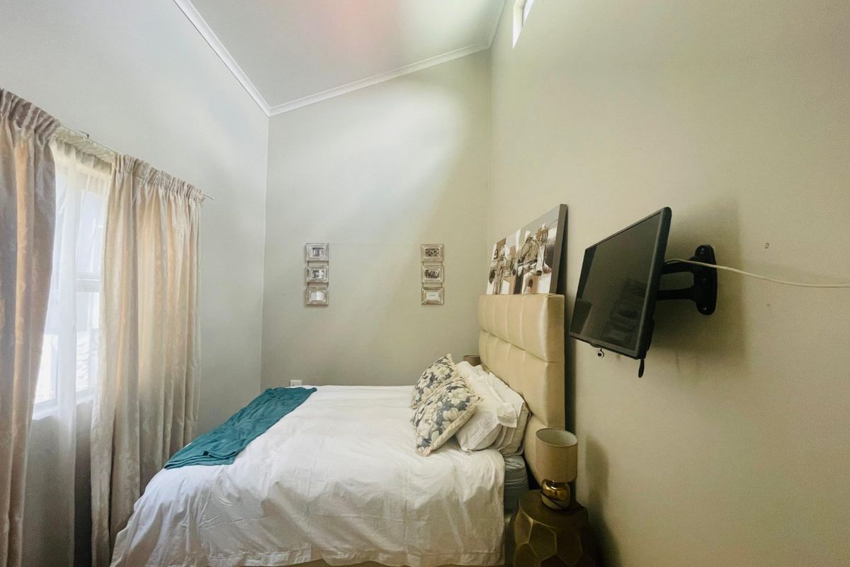 A well-maintained bedroom featuring a high vaulted ceiling, a clerestory window for natural light, and a wall-mounted television bracket.