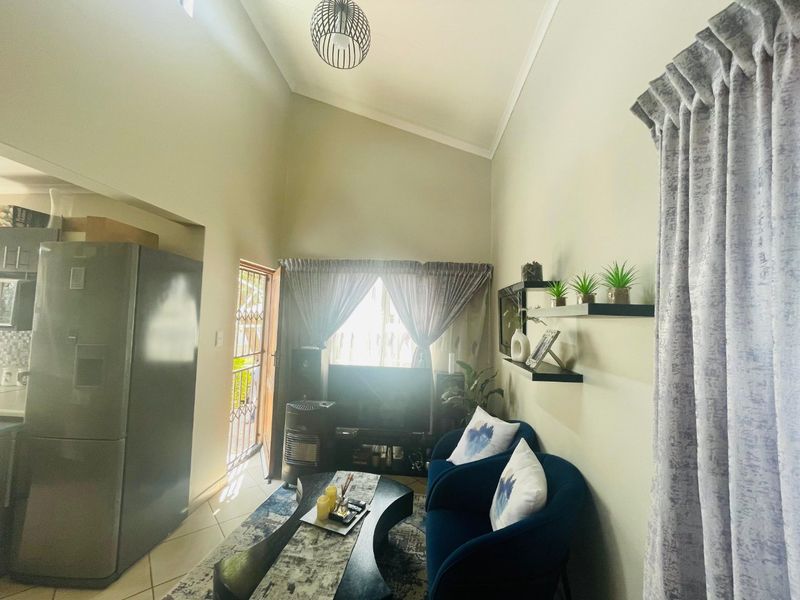 Open plan living area featuring high vaulted ceilings, tiled flooring, and direct access to an outdoor space through a security gate.