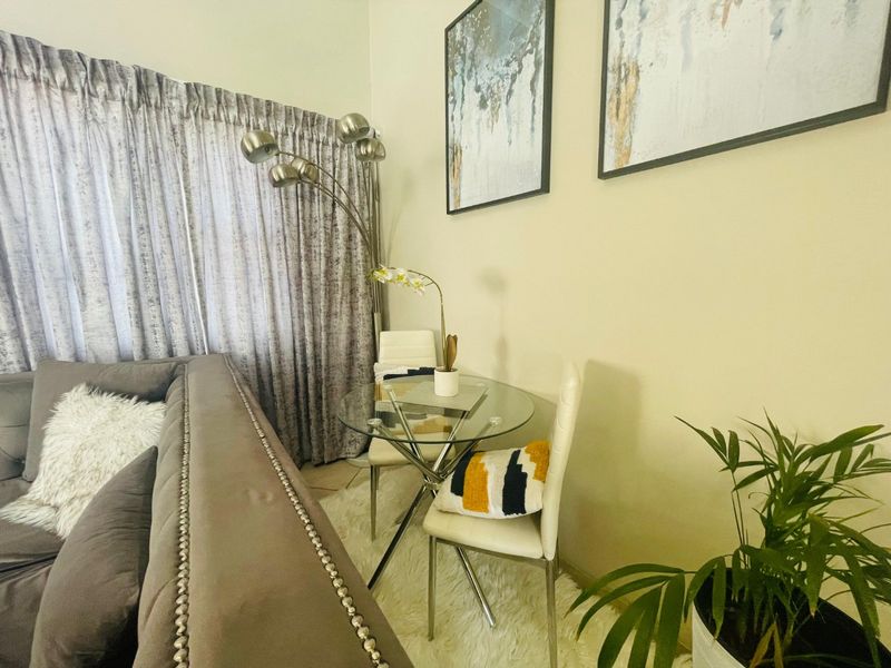 A cozy living room area featuring tiled flooring and floor-to-ceiling curtains, creating a comfortable and well-maintained space.