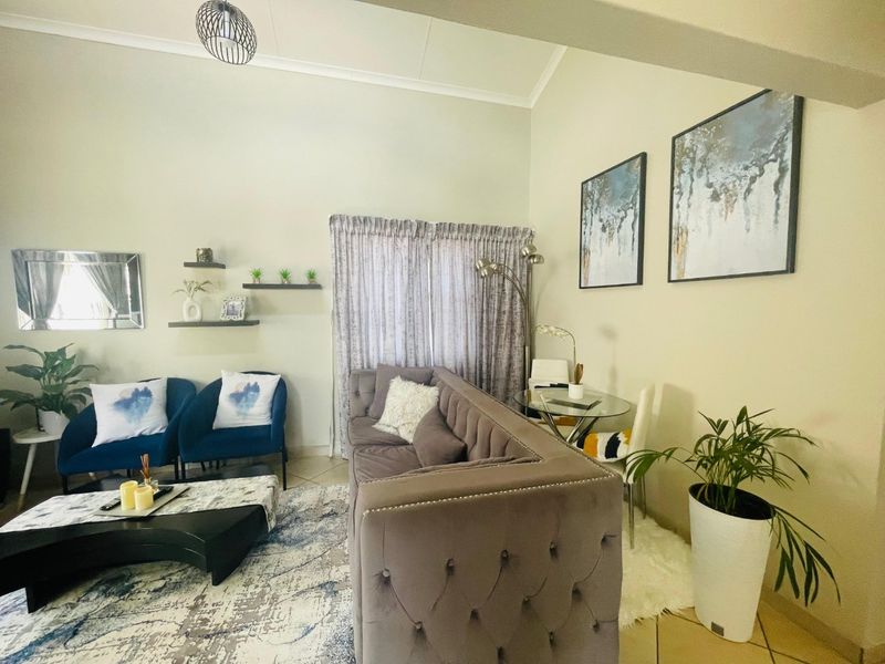 A spacious living room featuring high vaulted ceilings and neutral tiled flooring, offering a bright and comfortable atmosphere for relaxation.
