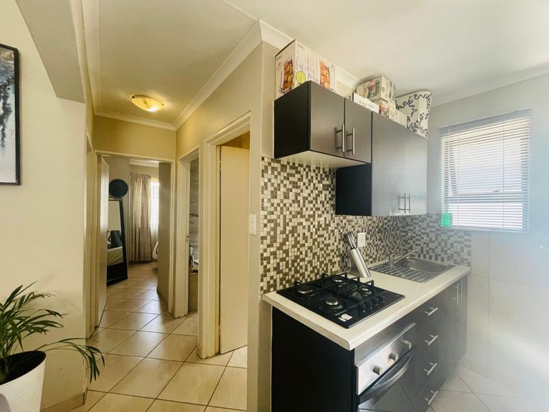 Compact kitchen featuring a gas hob, built-in oven, stainless steel sink, and mosaic tile backsplash with dark cabinetry.