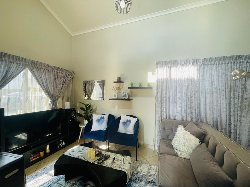 A bright living room featuring a high vaulted ceiling and tiled flooring, providing a spacious and comfortable atmosphere for relaxation.