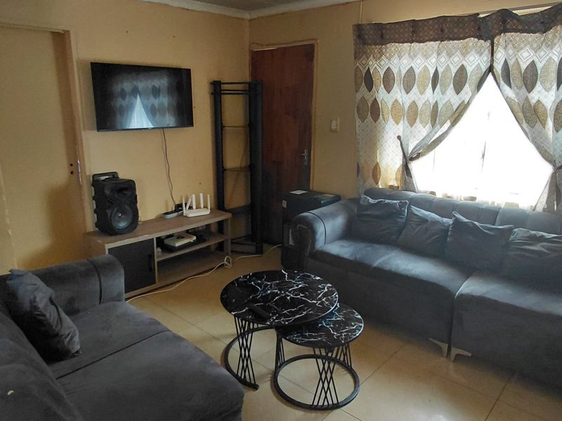 A compact living room featuring tiled flooring and neutral wall finishes, providing a functional space for relaxation.