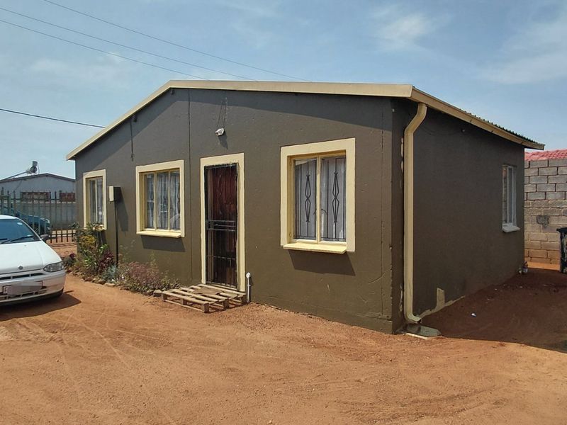 Front exterior view of a detached single-story house featuring painted walls, security gates, and security bars on windows.