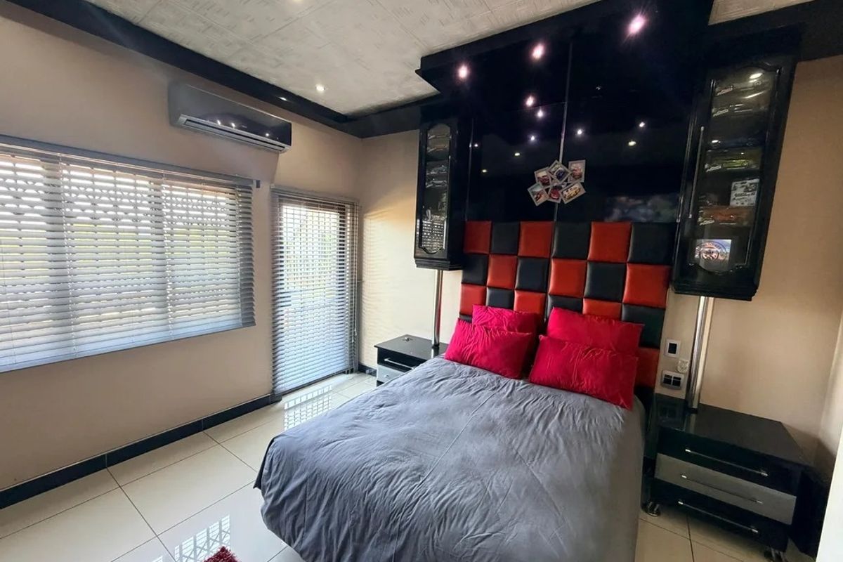 A modern bedroom featuring a custom built-in headboard with integrated display cabinetry, tiled flooring, and a split-system air conditioning unit.