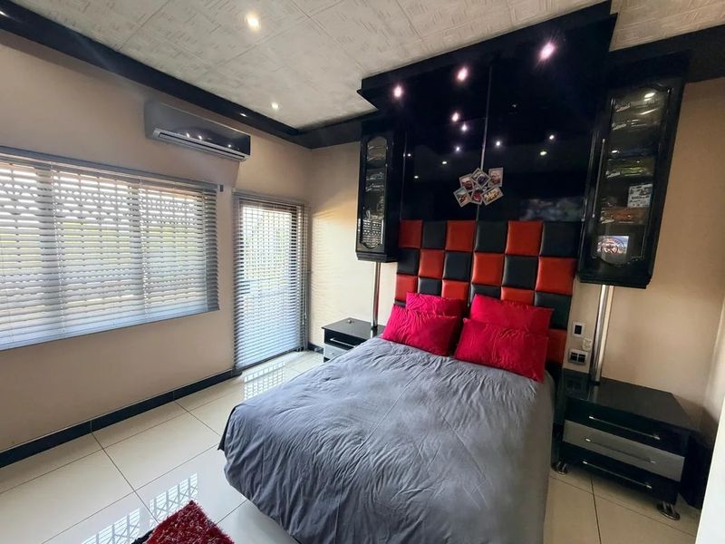 A modern bedroom featuring a custom built-in headboard with integrated display cabinetry, tiled flooring, and a split-system air conditioning unit.