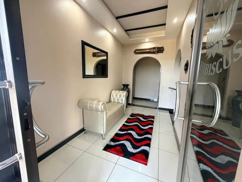 A bright entrance foyer featuring tiled flooring, recessed ceiling lighting, and an arched doorway leading into the home.