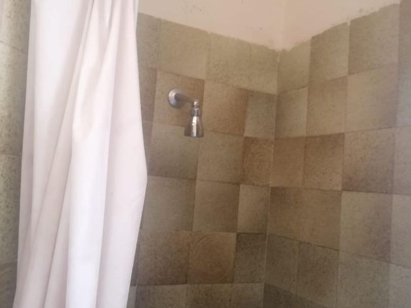 A dated shower enclosure featuring wall tiles and a standard shower head, requiring cosmetic updates to improve the bathroom aesthetic.