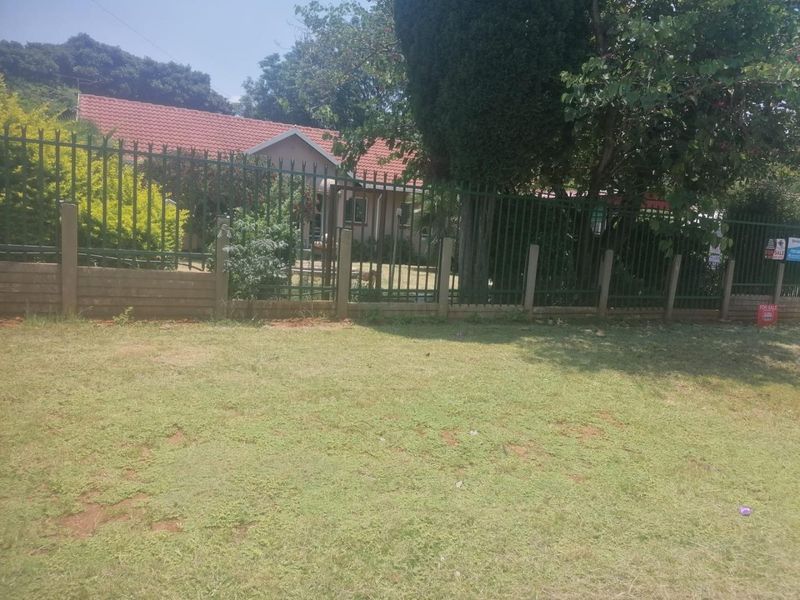 Front view of the property featuring a tiled roof house secured by metal palisade fencing and a concrete boundary wall.