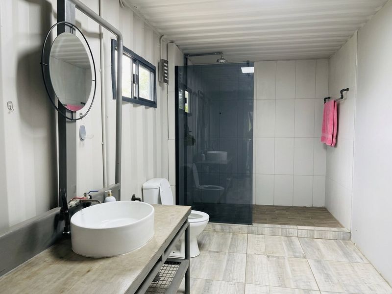 Modern industrial-style bathroom featuring a vessel sink vanity, walk-in shower with glass screen, and corrugated metal wall finishes.