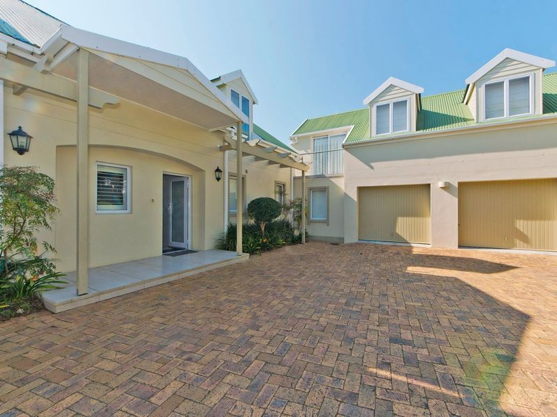Front exterior view of the property featuring a paved driveway, double garage, and a covered entrance porch with dormer windows above.