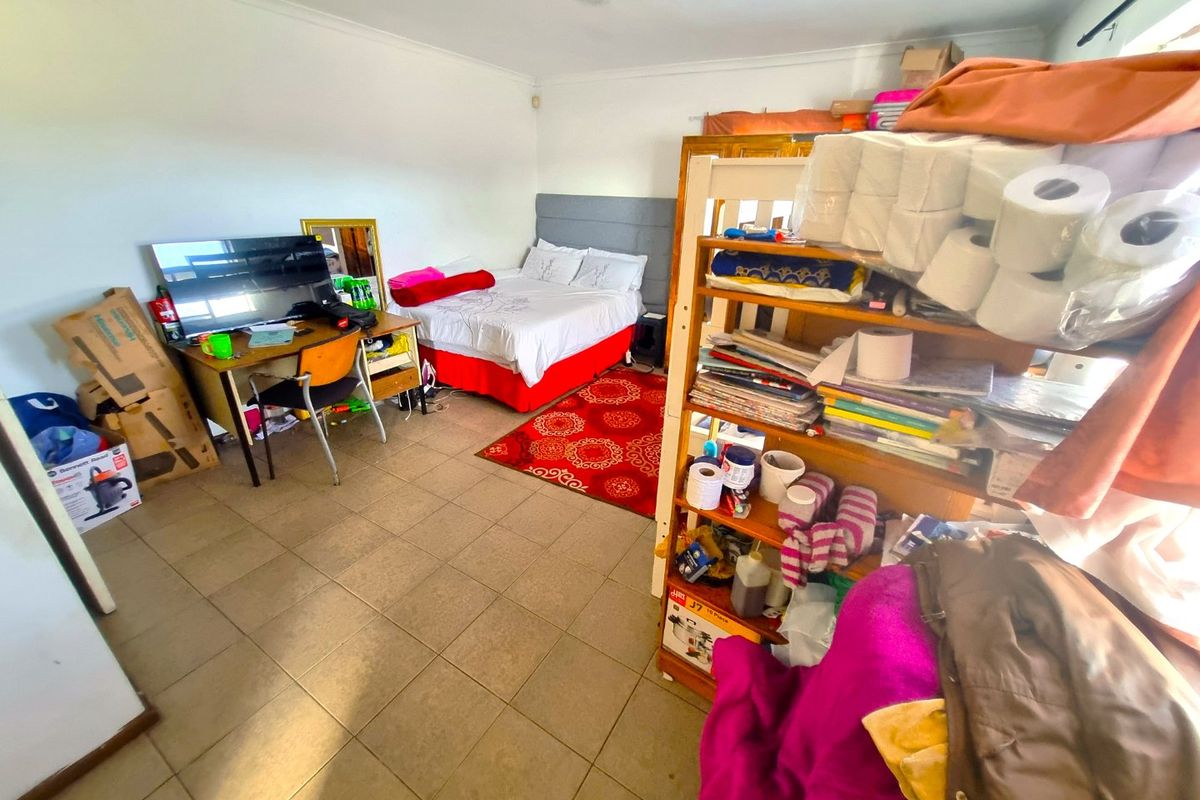 A bedroom featuring tiled flooring and coved ceilings, currently utilized as a multi-purpose living and storage space.